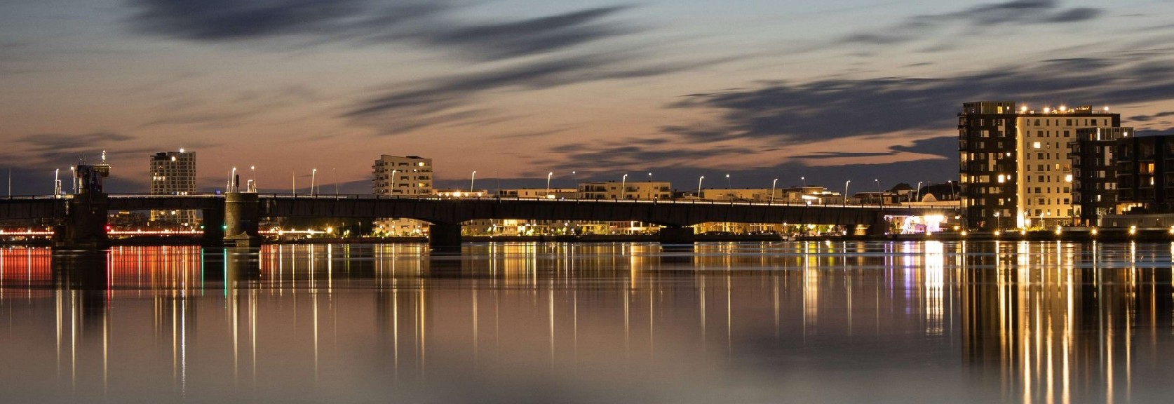 Aalborg havnefront i skumringen med bro og bylys spejlet i fjorden