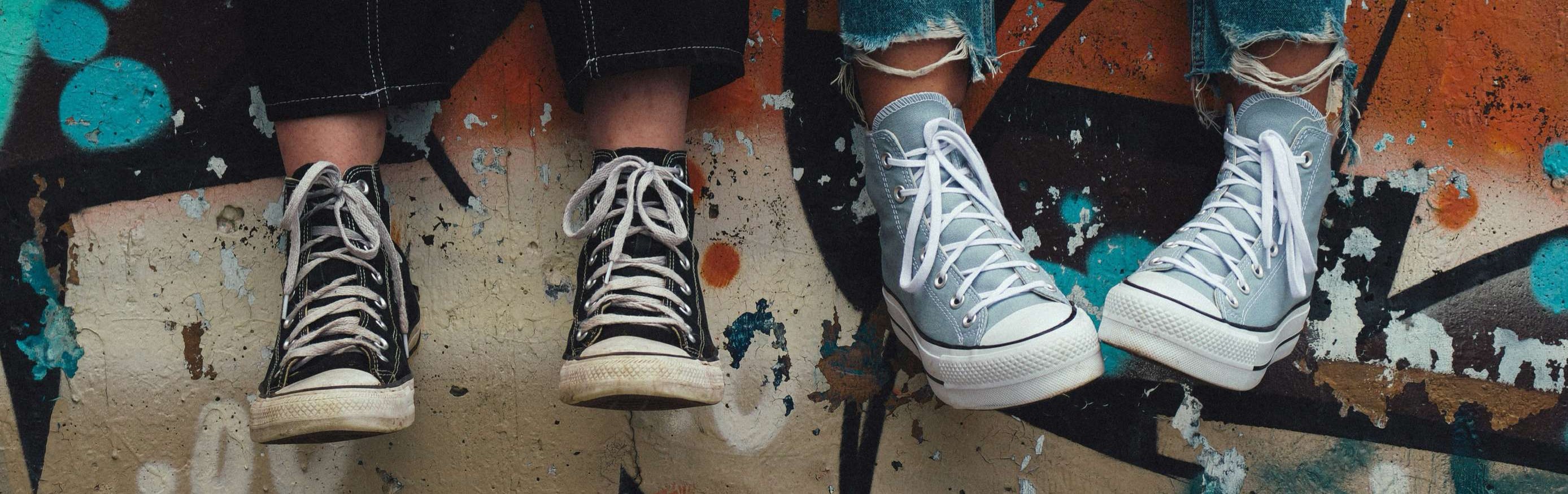 Unge fødder i sneakers foran farverig graffitivæg